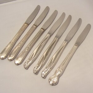 Puede incluir: Conjunto de siete cuchillos de mantequilla plateados. Los cuchillos tienen un dise&ntilde;o sencillo y elegante con un mango ligeramente curvado y una hoja lisa y puntiaguda. Los mangos presentan patrones florales y lineales decorativos.