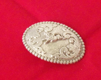 Hebilla de cinturón Nocona Rodeo vintage plateada de 8,25 cm (3 1/4") con jinete y toro salvaje.