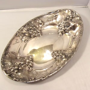 May include: A silver oval serving dish with a grapevine design. The dish is embossed with grapes and leaves.