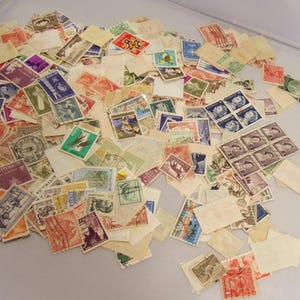May include: A large collection of vintage postage stamps from around the world. The stamps are in various colors and designs, including portraits, landscapes, and animals. Some of the stamps are in mint condition, while others show signs of wear and tear.
