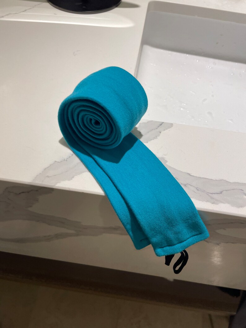 以下が含まれることがあります： 黒いストラップが付いた、ターコイズブルーの布のチューブが巻かれている