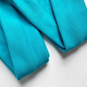 以下が含まれることがあります： ターコイズブルーの布地が2枚、折り畳まれています。布地は柔らかく、滑らかな質感です。