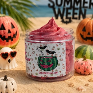 May include: A clear plastic jar filled with pink whipped soap, featuring a label with a watermelon jack-o'-lantern illustration, bats, and the text SCRUBBEDSOAP.COM. The jar is surrounded by small decorative pumpkins and a starfish.