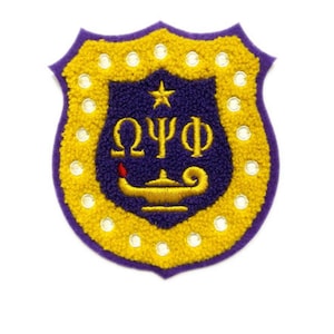 May include: A shield-shaped patch with a purple border and a yellow, textured outer layer. The inner shield is dark blue with a gold star and Greek letters. A gold lamp with a red flame is at the bottom. White circular accents are around the edge.
