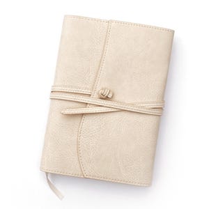 May include: A cream-colored leather journal with a knotted leather strap closure.