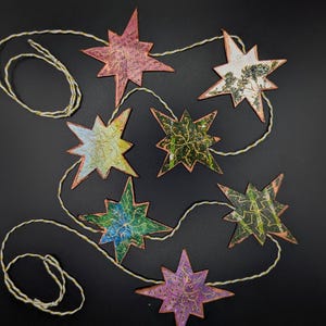 Handmade star garland: Seven  stars attached to white and gold cording . Made from recycled offcasts, Ships free