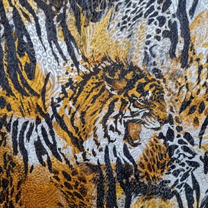 May include: A close-up of a fabric with a tiger print pattern in black, gold, and white. The fabric has a textured surface and a repeating pattern of tiger stripes and leopard spots.
