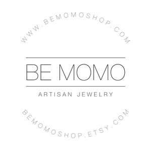 Puede incluir: Logotipo minimalista en blanco y negro. El texto "BE MOMO" se encuentra sobre "ARTISAN JEWELRY". Textos curvos arriba y abajo dicen "www.bemomoshop.com" y "bemomoshop.etsy.com". Dise&ntilde;o limpio y moderno.