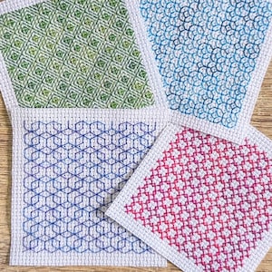 May include: Four square fabric coasters with different geometric patterns. The coasters are green, blue, red, and white.