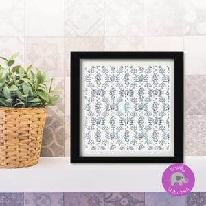May include: A framed artwork featuring a repeating pattern of seahorses, coral, and shells in navy blue on a white background. The artwork is in a black frame and sits on a white shelf. A potted plant in a woven basket is to the left.