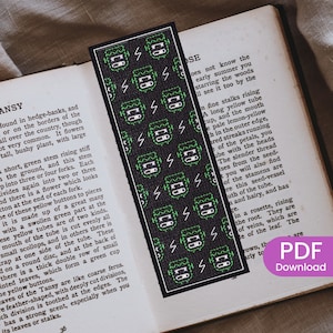 Puede incluir: Un marcapáginas negro y verde con un patrón repetido de un monstruo de Frankenstein con rayos. El marcapáginas está hecho de tela y tiene un diseño cosido.