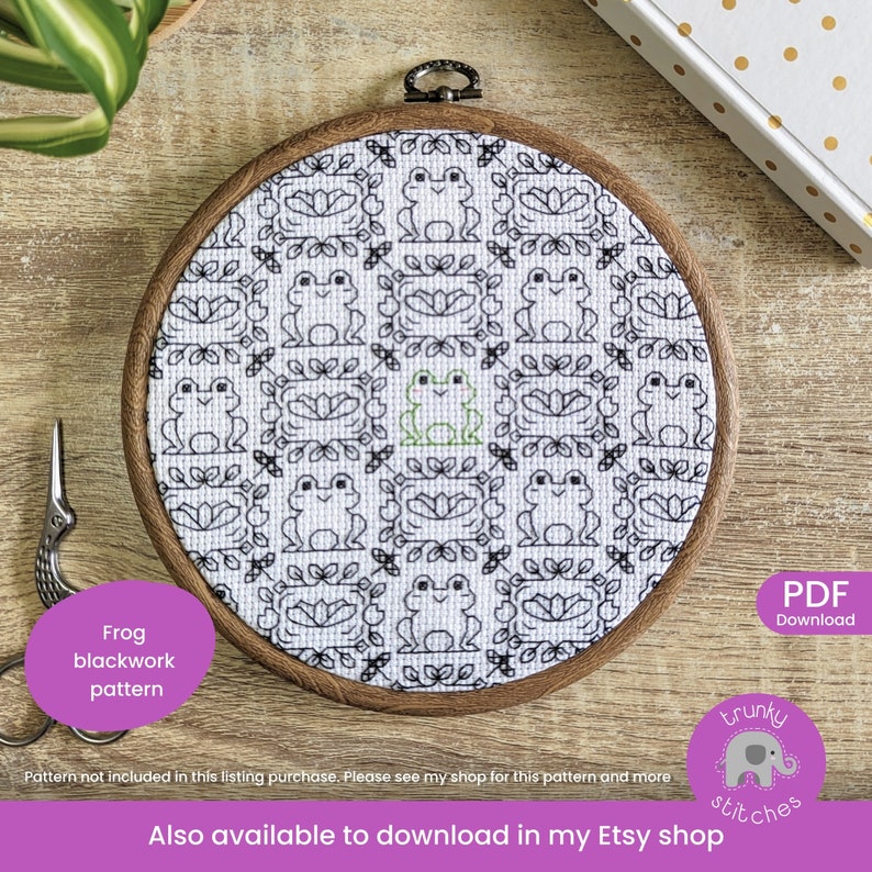 May include: A black and white cross stitch pattern of frogs in a square frame. The pattern is in a wooden embroidery hoop. The text "Frog blackwork pattern" is in a purple box below the hoop. The text "PDF Download" is in a white box with a black border in the upper right corner. The text "trunky stitches" is in a purple box with a white elephant in the lower right corner. The text "Also available to download in my Etsy shop" is below the hoop.