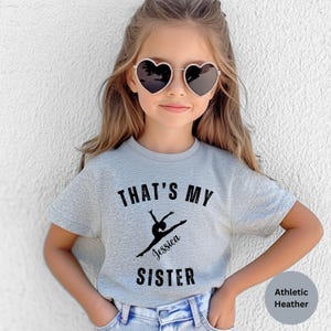 May include: Gray t-shirt with the text "That's My Sister" and a silhouette of a gymnast with the name "Jessica" printed on it.
