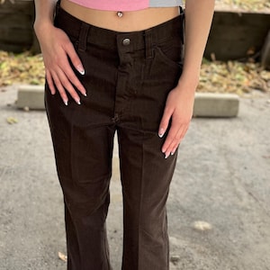 May include: Brown wide-leg pants with a high waist and a button fly. The pants are made of a soft, comfortable fabric and have a relaxed fit.