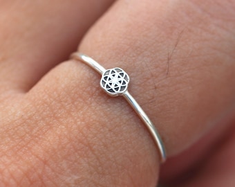 Op de afbeelding: Een zilveren ring met een klein, ingewikkeld geometrisch ontwerp in het midden.