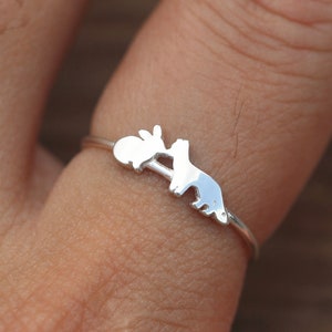 May include: A silver ring with a silhouette of a rabbit and a fox.