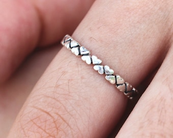May include: A silver ring with a band of small, connected heart shapes.