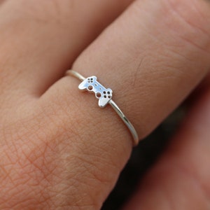 May include: A silver ring with a video game controller design.