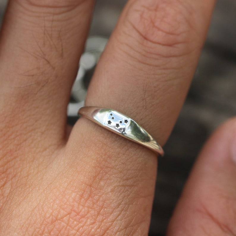 Puede incluir: Un anillo de plata con un peque&ntilde;o dise&ntilde;o de estrellas en la parte superior.