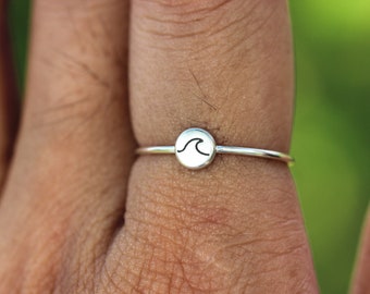 May include: A silver ring with a small, round wave design.