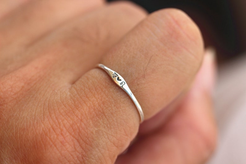 May include: A silver ring with a heart and the zodiac symbol for Virgo engraved on it.