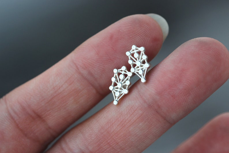 May include: A pair of silver earrings with a geometric design. The earrings are made of small, interconnected circles.