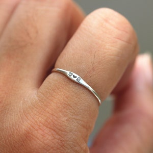 May include: A silver ring with the zodiac signs Virgo and Leo and a heart symbol between them.