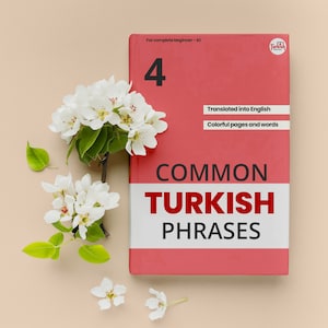 Op de afbeelding: Een rood boek met de titel "Common Turkish Phrases" en het nummer "4" op de omslag. Het boek is omringd door witte bloemen op een lichtbruine achtergrond.