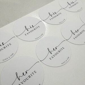 May include: Eight round white stickers with black calligraphy. The stickers say "his favourite" and "her favourite" with the names "Alice & Tom" at the bottom.
