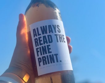 May include: A bottle of rose wine with a white label that says "Always read the fine print. You're going to be surprised."