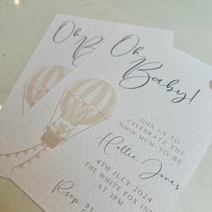 May include: A baby shower invitation with a hot air balloon illustration. The invitation reads "Oh Baby!" and includes the text "Join us to celebrate the soon mum-to-be Hollie Jones 4th July 2024 The White Fox Inn at 3pm RSVP by June 5th 07839 392313".
