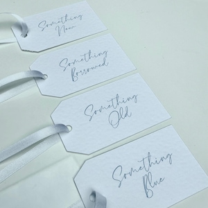 May include: Four white gift tags with blue calligraphy. The tags are labeled "Something New", "Something Borrowed", "Something Old", and "Something Blue".