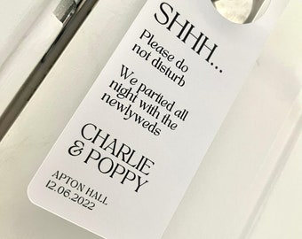 May include: White door hanger with the text "SHHH... Please do not disturb. We partied all night with the newlyweds CHARLIE & POPPY APTON HALL 12.06.2022"