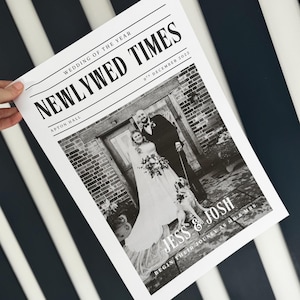 May include: A black and white newspaper-style print titled "NEWLYWED TIMES" with a wedding photo of a couple and their dog. The headline reads "WEDDING OF THE YEAR" and the date is "9th December 2022". The names "Jess & Josh" are featured.