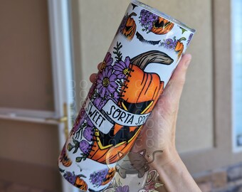 May include: A white tumbler with a Halloween-themed design. The design features a pumpkin with a stitched-up mouth, purple flowers, and the text "Sorta Sweet, Not Really". A cat is sitting in a teacup at the bottom of the tumbler.