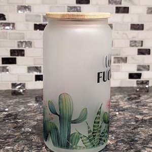 May include: A frosted glass jar with a bamboo lid and a cactus design. The jar has the text "Coffee is my F*cking Therapy" printed on it.