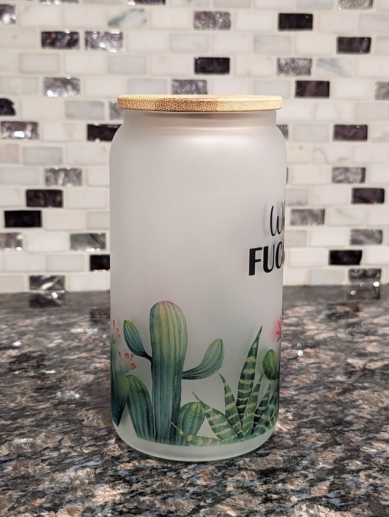 May include: A frosted glass jar with a bamboo lid and a cactus design. The jar has the text "Coffee is my F*cking Therapy" printed on it.