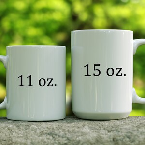 May include: Two white ceramic mugs with black text. The smaller mug is 11 oz and the larger mug is 15 oz.