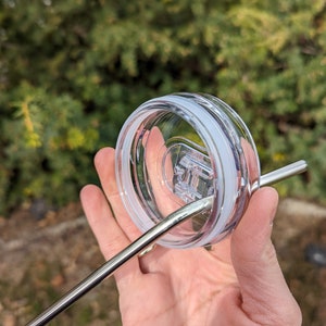 Puede incluir: Tapa de pl&aacute;stico transparente con un anillo de silicona blanco y una pajita de acero inoxidable insertada a trav&eacute;s de un agujero en la tapa.