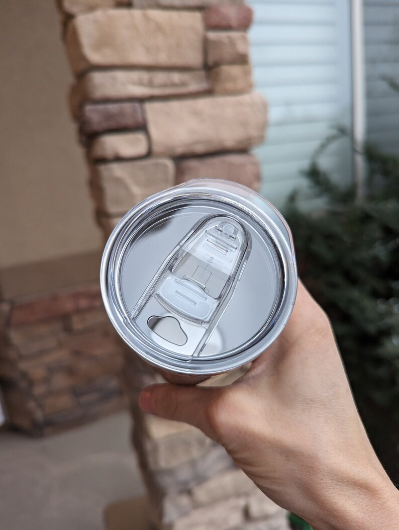 May include: A stainless steel travel mug with a clear lid and a slider to open and close the lid.