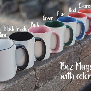 May include: Seven 15oz mugs with different colored rims. The mugs are white with black handles. The colors of the rims are black, pink, green, blue, red, and orange. The text "15oz Mugs with color" is written below the mugs.
