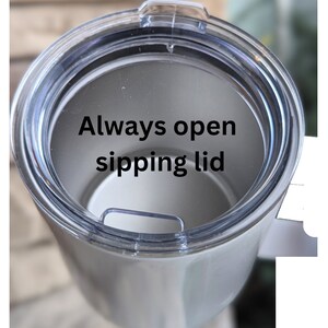 May include: A white stainless steel tumbler with a clear plastic lid. The lid has a small opening for sipping and the text "Always open sipping lid" is printed on the inside of the lid.