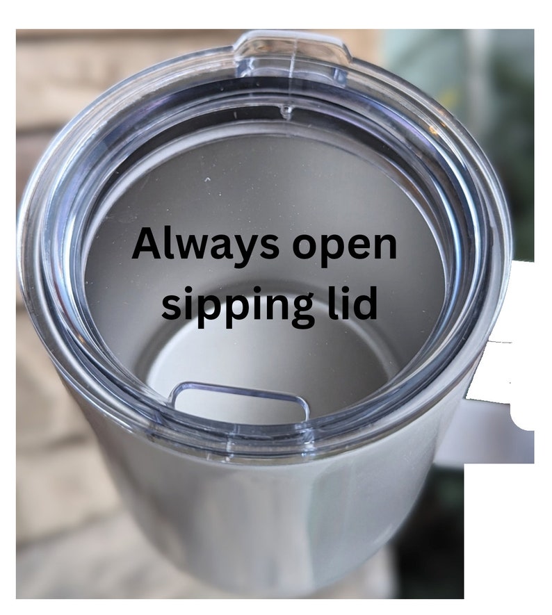 May include: A white stainless steel tumbler with a clear plastic lid. The lid has a small opening for sipping and the text "Always open sipping lid" is printed on the inside of the lid.