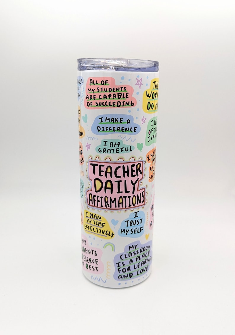 Op de afbeelding: Een witte beker met kleurrijke tekst en illustraties. De tekst bevat "Teacher Daily Affirmations" en zinnen als "All of my students are capable of succeeding", "I make a difference", "I am grateful", "I plan my time effectively", "I trust myself", en "My classroom is a place for learning and love".