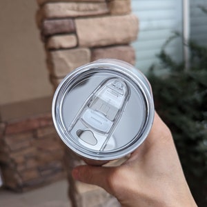 May include: A stainless steel travel mug with a clear lid and a slider to open and close the lid.