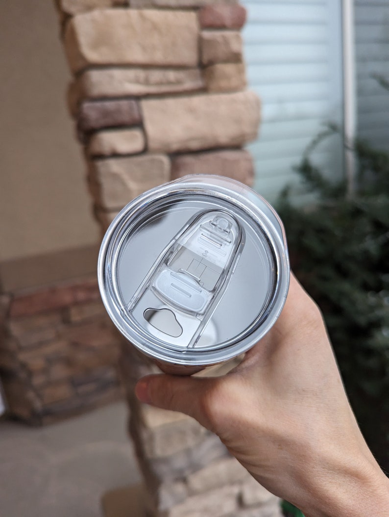 May include: A stainless steel travel mug with a clear lid and a slider to open and close the lid.