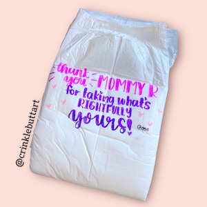 May include: A white adult diaper with pink and purple writing that says "Thank you Mommy R for taking what's rightfully yours!" with a pink heart and butterfly design.