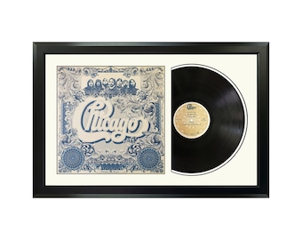 May include: A framed black vinyl record with a black and white image of the band Chicago on the cover. The album cover features a blue and white ornate design with the band's name in white lettering. The record is in a black frame with a white mat.