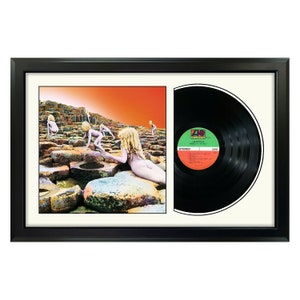 May include: A framed black vinyl record with a black and white album cover featuring a group of people standing on a rocky shore. The album cover is titled "Wish You Were Here" and the record label is "Atlantic Records".