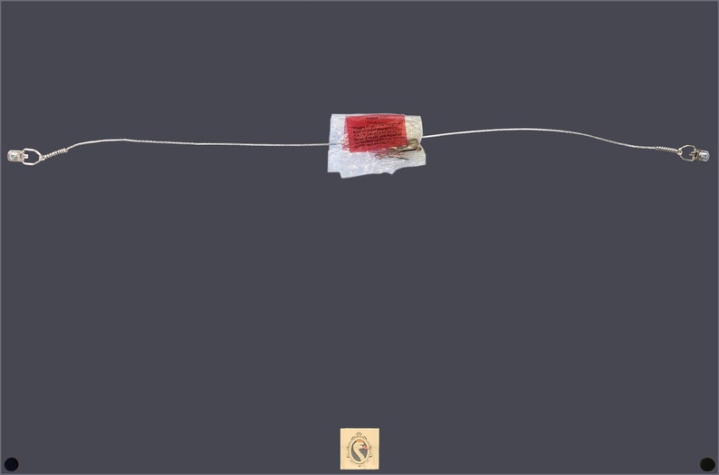 May include: A silver wire cable with a red and white label attached to it. The cable has a small silver connector on each end.